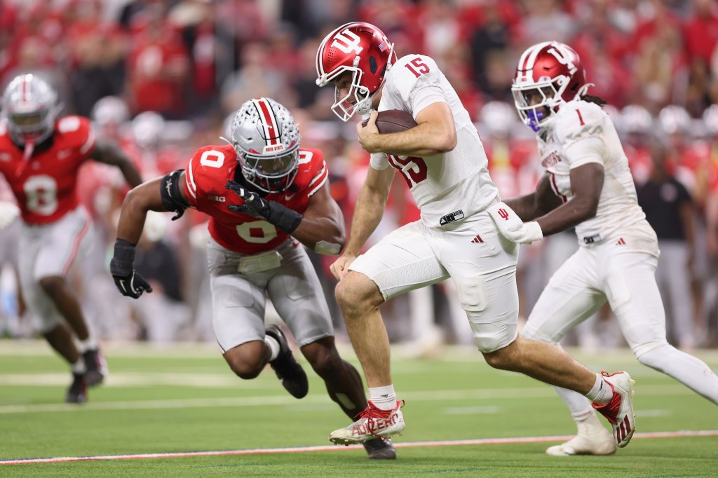 Indiana Hoosier Fernando Mendoza (#15) scrambling with the ball, defended by Ohio State Buckeye Sonny Styles (#0).