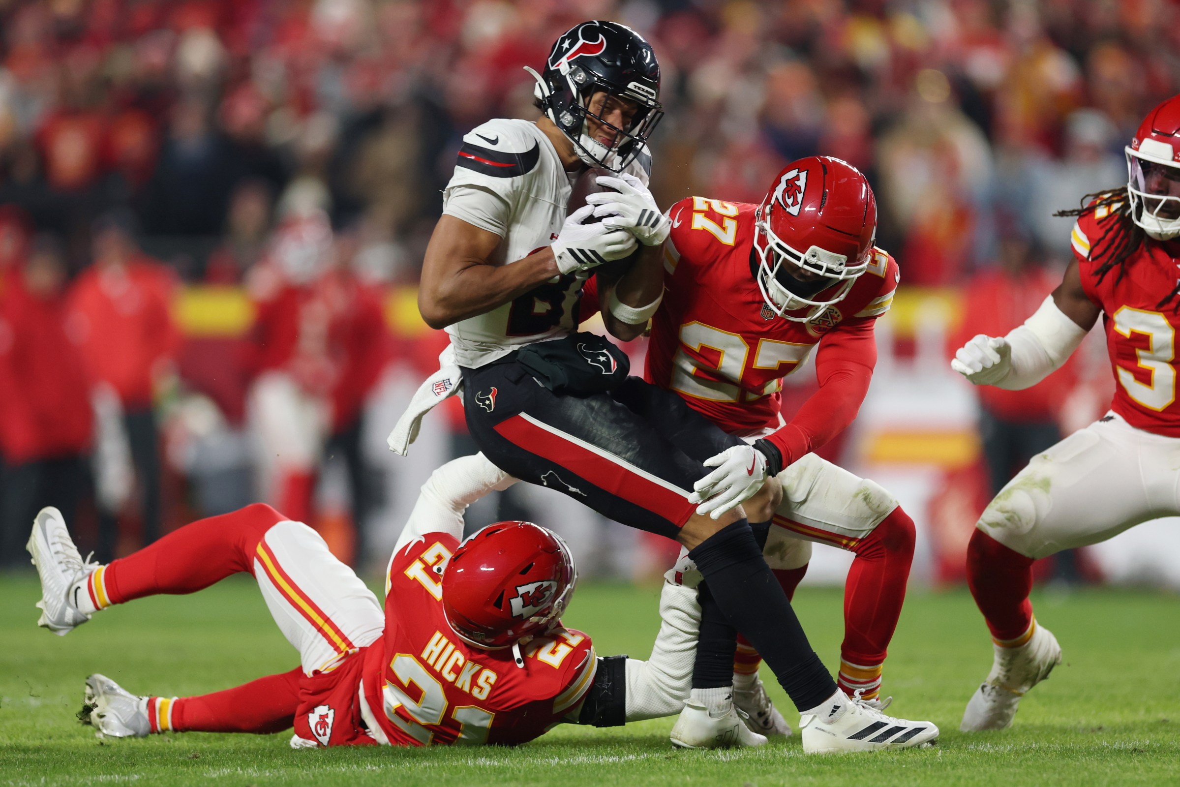 KANSAS CITY, MISSOURI - DECEMBER 07: Jayden Higgins #81 of the Houston Texans is tackled after his reception by Jaden Hicks #21 and Chamarri Conner #27 of the Kansas City Chiefs during the fourth quarter at Arrowhead Stadium on December 07, 2025 in Kansas City, Missouri. (Photo by Jamie Squire/Getty Images)