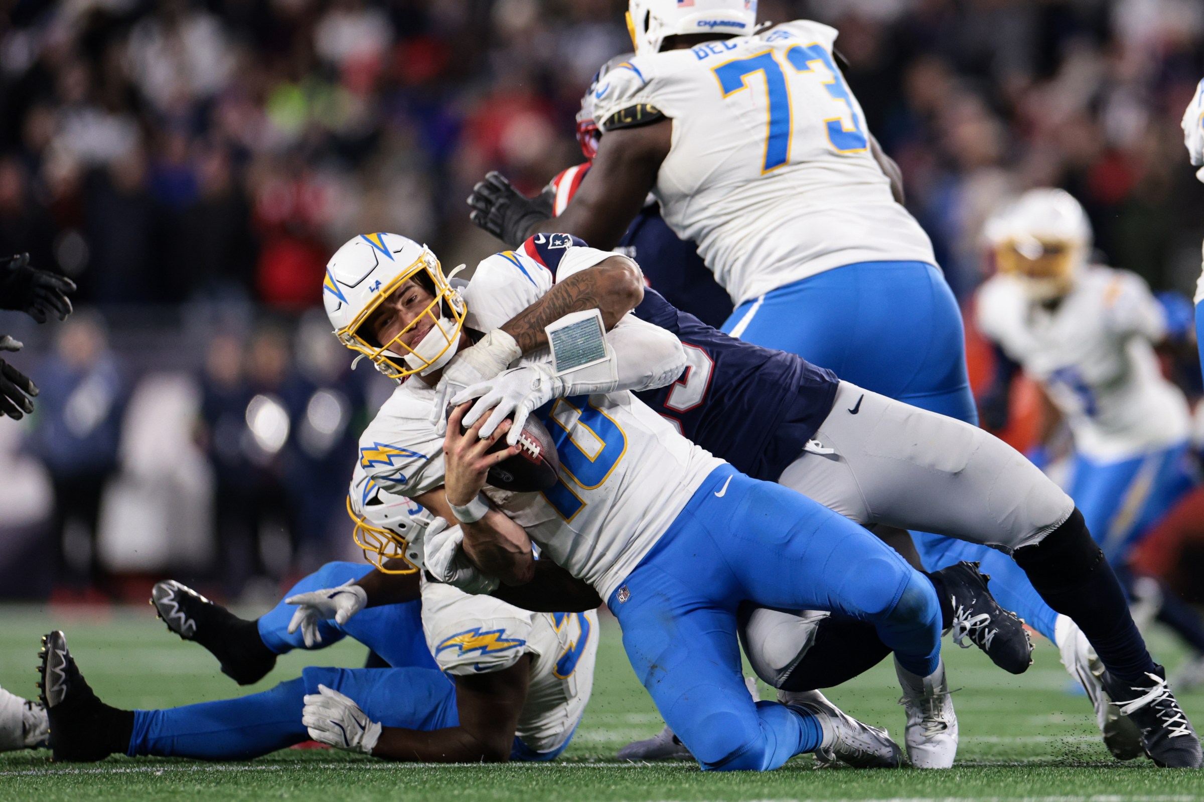 FOXBOROUGH, MASSACHUSETTS - JANUARY 11: Justin Herbert #10 of the Los Angeles Chargers is sacked by Anfernee Jennings #33 of the New England Patriots in the fourth quarter of an AFC wild card playoff football game on January 11, 2026 in Foxborough, Massachusetts. (Photo by Kathryn Riley/Getty Images)