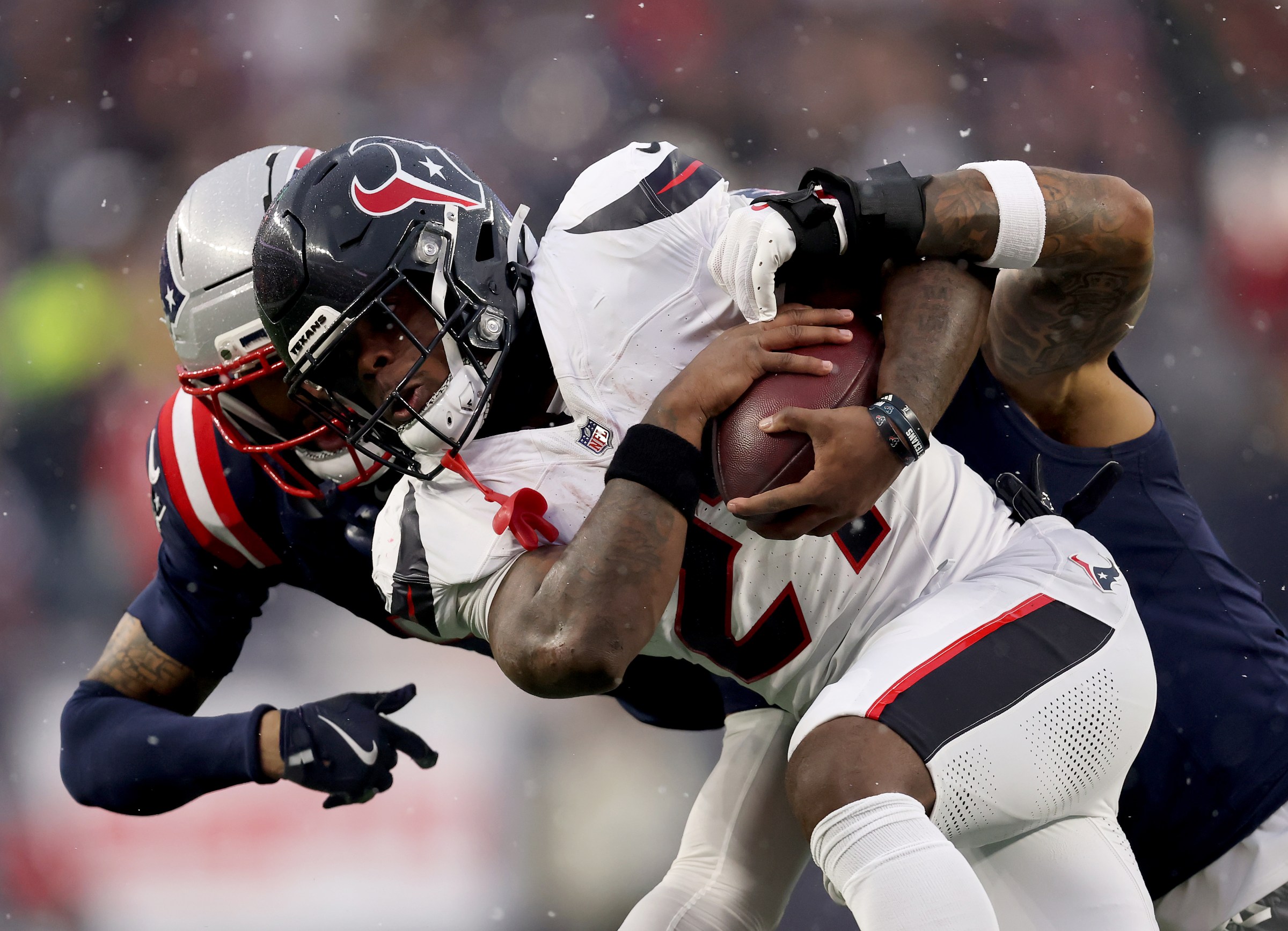 FOXBOROUGH, MASSACHUSETTS - JANUARY 18: Woody Marks #27 of the Houston Texans carries the ball as Harold Landry III #2 and Carlton Davis III #7 of the New England Patriots defend during the AFC Divisional Playoff game at Gillette Stadium on January 18, 2026 in Foxborough, Massachusetts. (Photo by Elsa/Getty Images)
