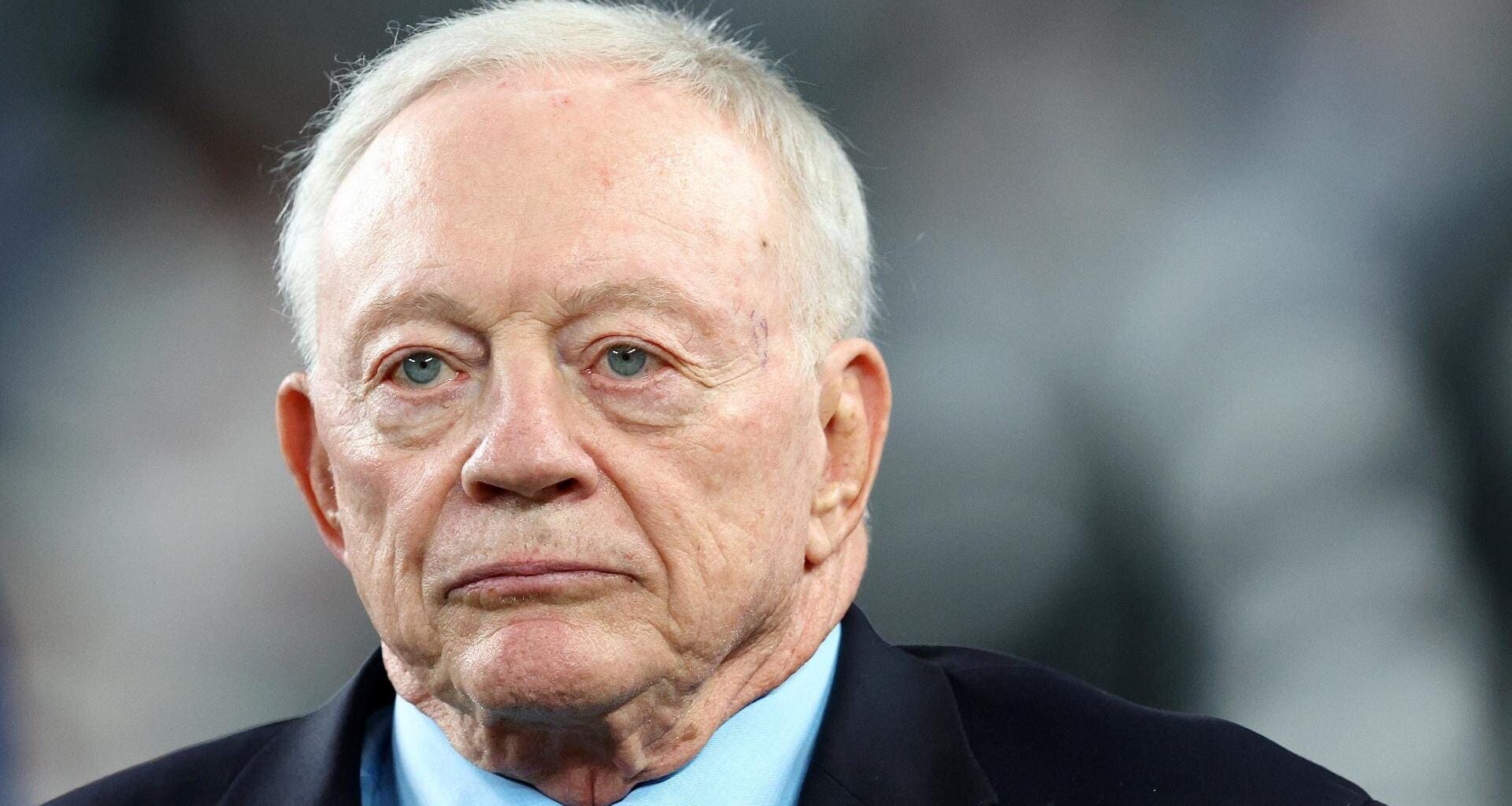 A man in a suit and tie looks ahead with a serious expression as head of the Dallas Cowboys.