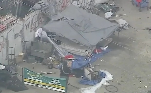 Former Philadelphia Eagle Kevin Johnson and three other people have been murdered at this homeless encampment in metro Los Angeles over the past four months. Visible is a green sign posted by local law enforcement with phone numbers to reach the homicide bureau or leave anonymous tips. (KABC-TV)