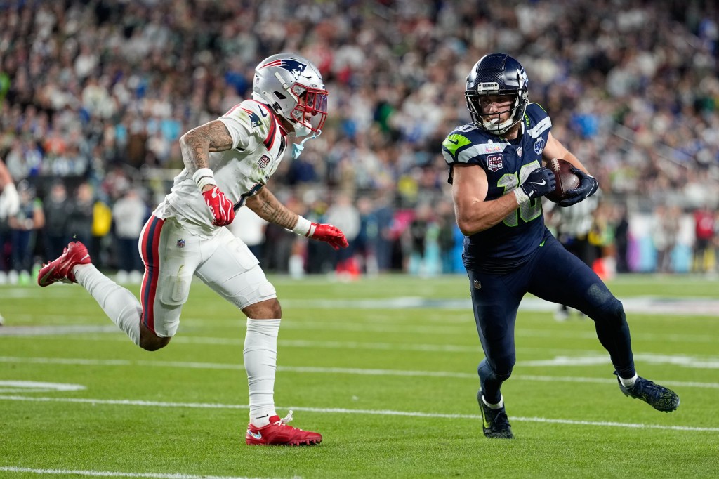 Seattle Seahawks wide receiver Cooper Kupp runs with the football away from a New England Patriots defender during Super Bowl 60.