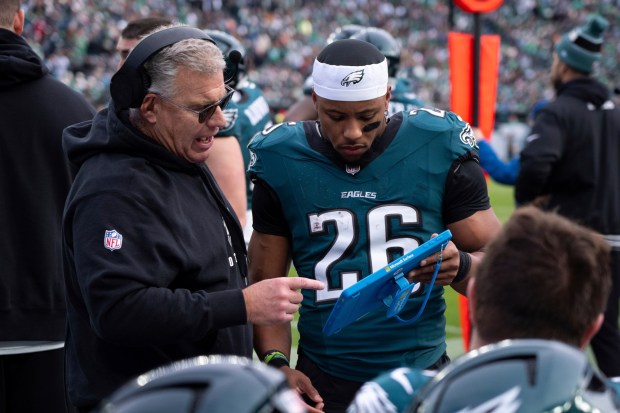 Eagles offensive line coach Jeff Stoutland, left, talks with running back Saquon Barkley during a game against the Carolina Panthers Dec. 8, 2025, at Lincoln Financial Field. (Chris Szagola/AP)