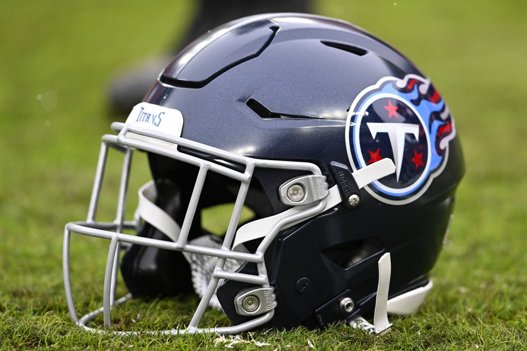 A dark blue Tennessee Titans football helmet with a white face mask on a grassy field.