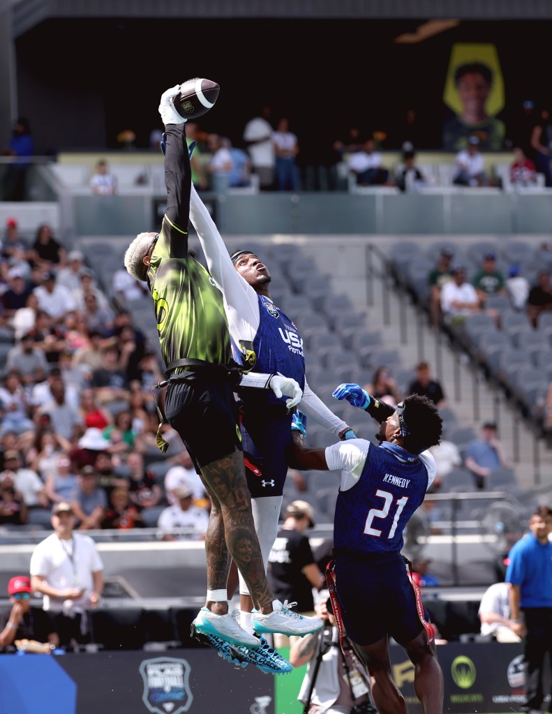 Odell Beckham Jr. catching a football over two defenders during a flag football game.