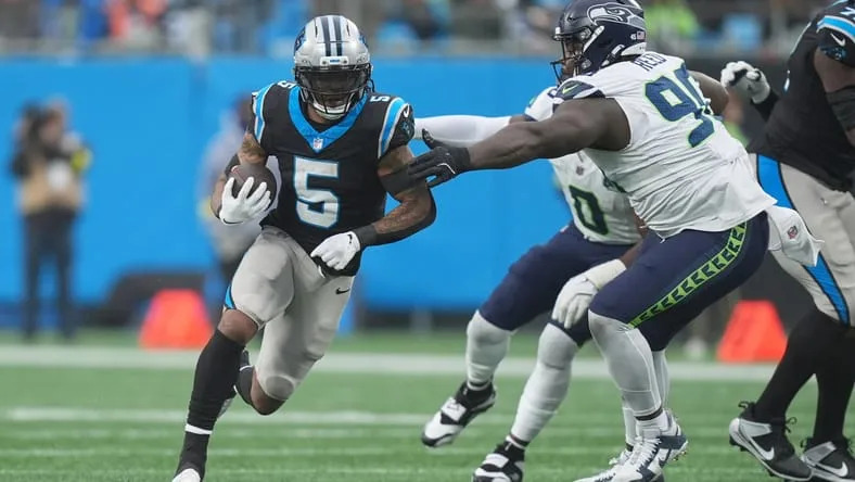 Rico Dowdle running the ball while Jarran Reed pursues during a Panthers and Seahawks game. Vikings running back free agency.