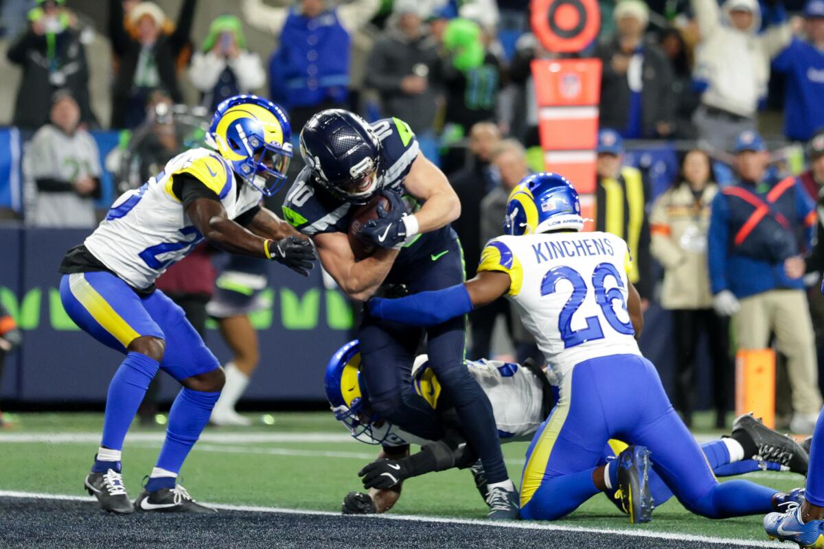 Seattle's Cooper Kupp, center, tries to power his way through the tackles Rams defenders Roger McCreary and Kamren Kinchens.