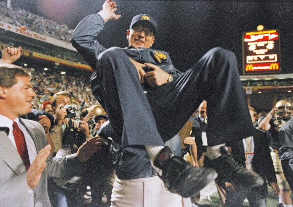 FILE - Notre Dame head coach Lou Holtz is raised up to be carried off the field after his team defeated West Virginia in the Fiesta Bowl to win the national college football championship, Jan. 2, 1989, in Tempe, Ariz.  (AP Photo/Rob Schumacher, File)