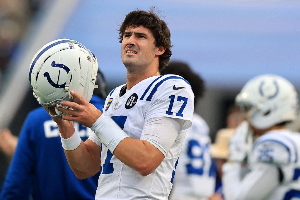 Indianapolis Colts quarterback Gardner Minshew looks up, holding his helmet in his hands.