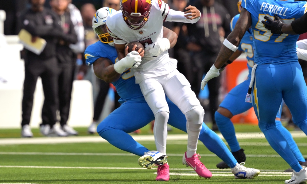 Oct 5, 2025; Inglewood, California, USA; Los Angeles Chargers defensive end Da'Shawn Hand (91) sacks Washington Commanders quarterback Jayden Daniels (5) in the first half at SoFi Stadium.