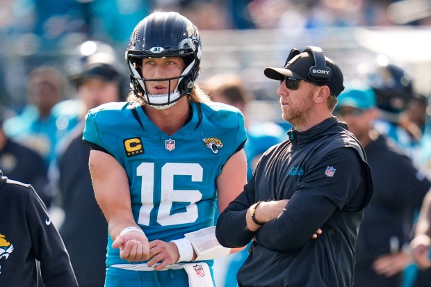 Jacksonville Jaguars quarterback Trevor Lawrence talks with head coach Liam Coen during the first half of an NFL wild card playoff game against the Buffalo Bills, Sunday, Jan. 11, 2026, in Jacksonville, Fla. (AP Photo/John Raoux)