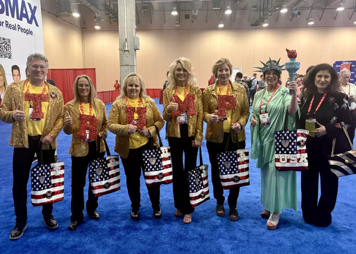 The Trump Tribe of Texas poses for a photo at CPAC, wearing gold jackets with bold, bedazzled red letters spelling 'TRUMP,' while one member is dressed as the Statue of Liberty.