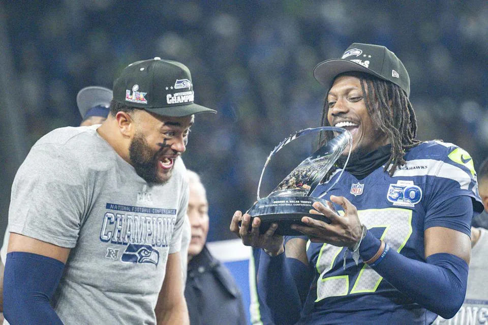 Seattle Seahawks defensive end Mike Morris (94), left, and Seattle Seahawks cornerback Riq Woolen (27) react to the NFC Championship trophy at Lumen Field, on Sunday, Jan. 25, 2026, in Seattle.