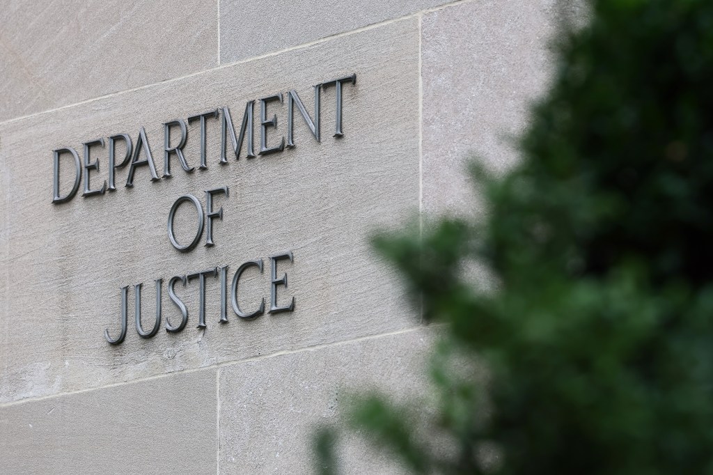 The words "Department of Justice" are carved into a light grey stone wall.