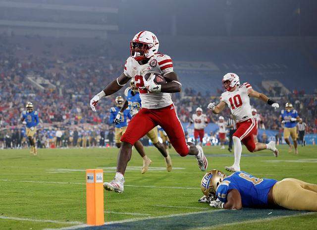 PASADENA, CALIFORNIA - NOVEMBER 08: Emmett Johnson #21 of the Nebraska Cornhuskers runs past Jonjon Vaughns #6 of the UCLA Bruins for a touchdown, to take a 28-7 lead, during a 28-21 win over the UCLA Bruins at Rose Bowl Stadium on November 08, 2025 in Pasadena, California. (Photo by Harry How/Getty Images)