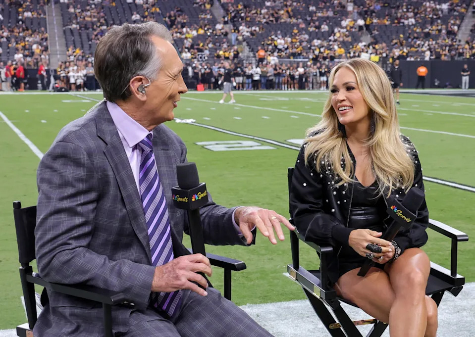 LAS VEGAS, NEVADA - SEPTEMBER 24: NBC Sunday Night Football color commentator Cris Collinsworth (L) talks with recording artist Carrie Underwood before a game between the Pittsburgh Steelers and the Las Vegas Raiders at Allegiant Stadium on September 24, 2023 in Las Vegas, Nevada. The Steelers defeated the Raiders 23-18. (Photo by Ethan Miller/Getty Images)Ethan Miller/Getty Images
