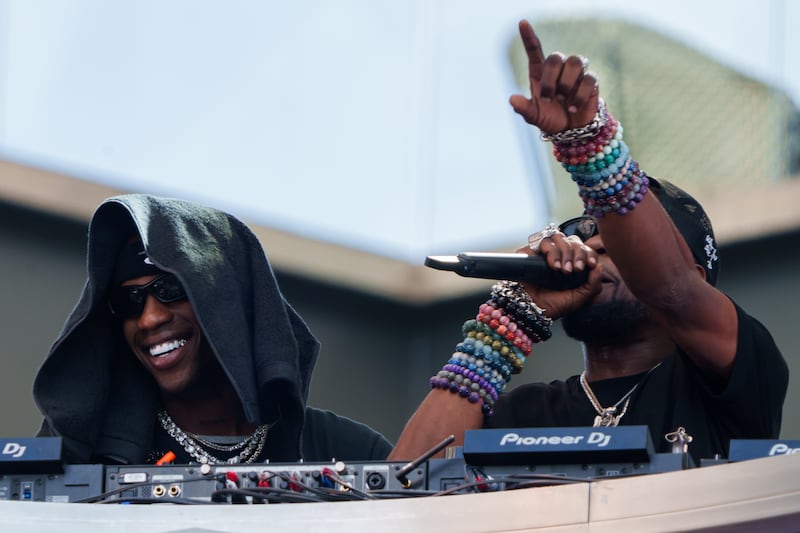 Shot of Travis Scott DJing at BMO Stadium with black sunglasses and a black towel over his head.