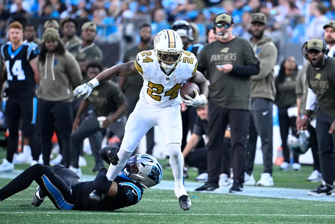 Nov 9, 2025; Charlotte, North Carolina, USA; New Orleans Saints running back Devin Neal (24) with the ball as Carolina Panthers safety Tre'von Moehrig (7) defends in the fourth quarter at Bank of America Stadium. Mandatory Credit: Bob Donnan-Imagn Images