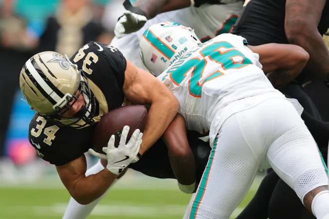 Nov 30, 2025; Miami Gardens, Florida, USA; New Orleans Saints running back Evan Hull (34) is tackled by. Miami Dolphins cornerback Rasul Douglas (26) during the second half at Hard Rock Stadium. Mandatory Credit: Sam Navarro-Imagn Images
