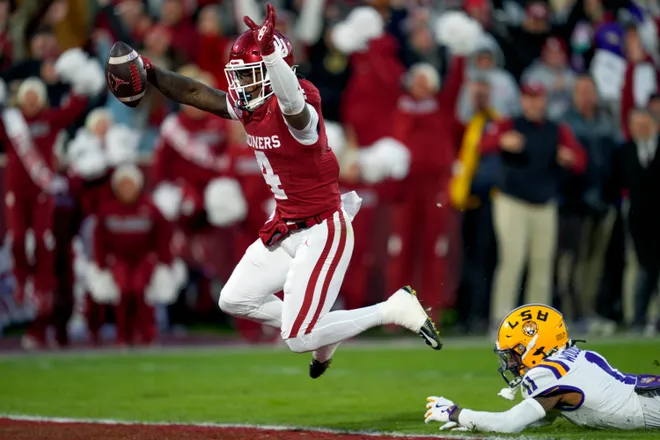 Oklahoma Sooners wide receiver Deion Burks (4) leaps to the end zone past Louisiana State Tigers cornerback PJ Woodland (11) to score a touchdown during a college football game between the University of Oklahoma Sooners (OU) and the LSU Tigers at Gaylord Family – Oklahoma Memorial Stadium in Norman, Okla., Saturday, Nov. 29, 2025. Oklahoma won 17-13.