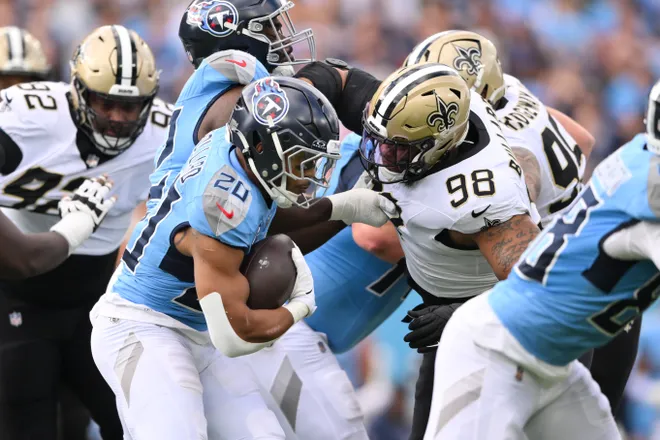 Dec 28, 2025; Nashville, Tennessee, USA; Tennessee Titans running back Tony Pollard (20) runs the ball against New Orleans Saints defensive end Jonathan Bullard (98) during the first quarter of the game at Nissan Stadium. Mandatory Credit: Steve Roberts-Imagn Images
