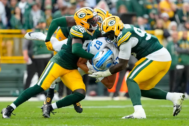 Sep 7, 2025; Green Bay, Wisconsin, USA; Green Bay Packers linebacker Edgerrin Cooper (56) and Green Bay Packers defensive tackle Colby Wooden (96) tackle an airborne Detroit Lions tight end Sam LaPorta (87) during the fourth quarter at Lambeau Field. Mandatory Credit: Jeff Hanisch-Imagn Images