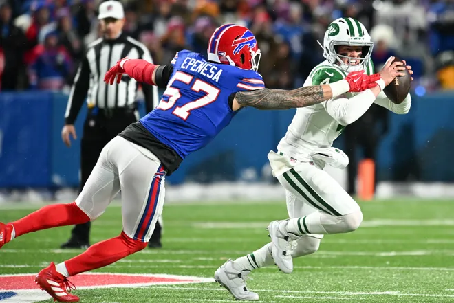 Jan 4, 2026; Orchard Park, New York, USA; New York Jets quarterback Brady Cook (4) scrambles with the ball under pressure from Buffalo Bills defensive end AJ Epenesa (57) during the first half at Highmark Stadium. Mandatory Credit: Mark Konezny-Imagn Images