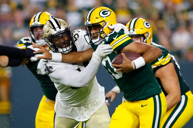 Aug 19, 2022; Green Bay, Wisconsin, USA; Green Bay Packers quarterback Jordan Love (10) is tackled by New Orleans Saints defensive end Taco Charlton (54) during the second quarter at Lambeau Field. Mandatory Credit: Jeff Hanisch-USA TODAY Sports