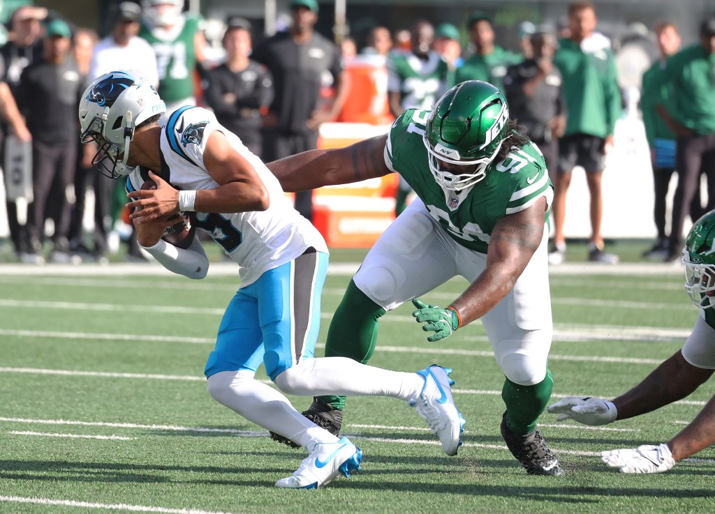 Carolina Panthers player Bryce Young running with the ball as New York Jets player Jowon Briggs rushes him.