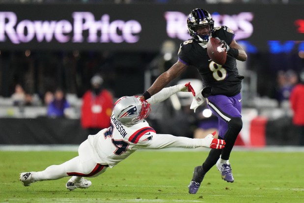 Baltimore Ravens quarterback Lamar Jackson (8) runs against New England Patriots linebacker K'Lavon Chaisson during the first half of an NFL football game, Sunday, Dec. 21, 2025, in Baltimore. (AP Photo/Stephanie Scarbrough)