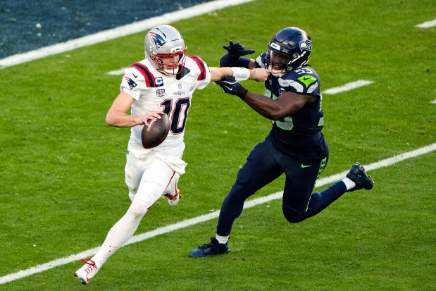New England Patriots quarterback Drake Maye (10) fights off pressure from Seattle Seahawks linebacker Boye Mafe (53) before throwing a pass during the first half of the NFL Super Bowl LX. (AP Photo/Charlie Riedel)