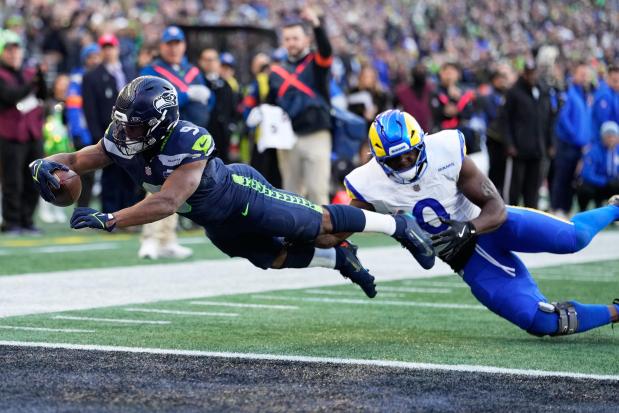 Seattle Seahawks running back Kenneth Walker III (9) scores a touchdown past Los Angeles Rams linebacker Byron Young (0) during the first half of the NFC Championship Game on Sunday, Jan. 25, 2026, in Seattle. (AP Photo/Stephen Brashear)