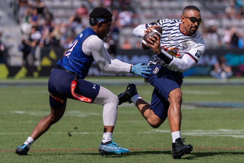 Isaiah Calhoun grabs at Jalen Hurts' flags as Hurts runs by with the football.