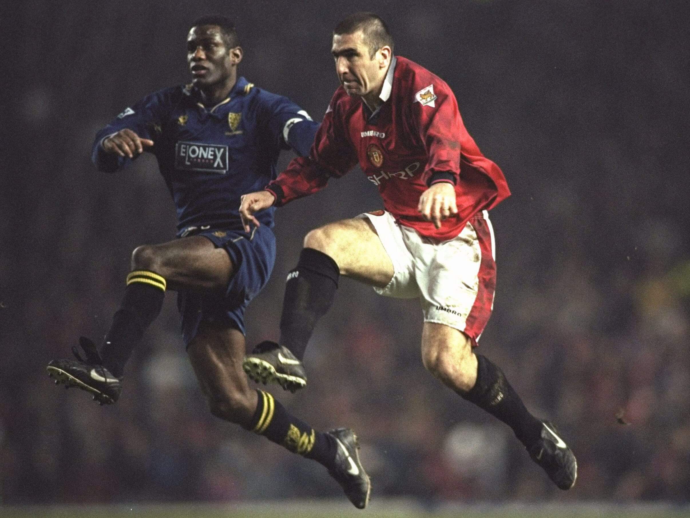Robbie Earle competes for possession with Manchester United's Eric Cantona