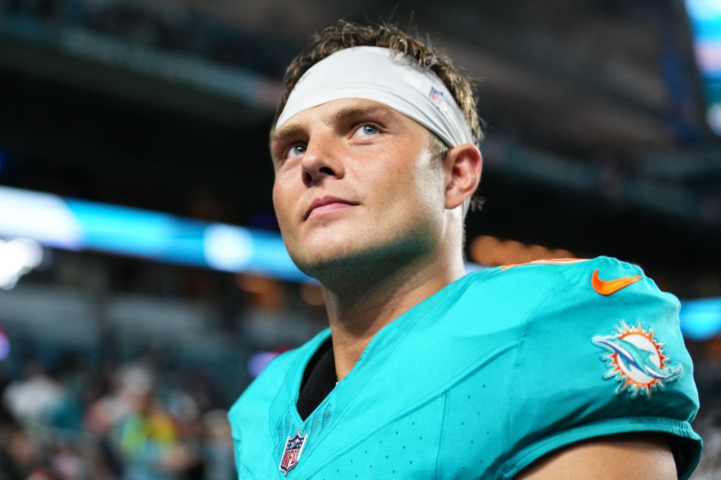 Close-up of a Miami Dolphins player in a teal jersey and white headband, looking up.