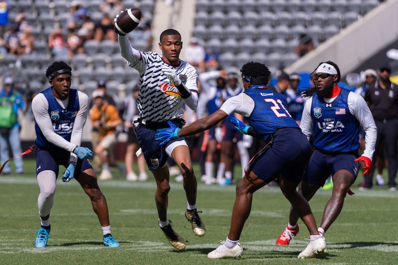 Founders FFC receiver DeVonta Smith with football in hand trying to navigate around three Team USA defenders.