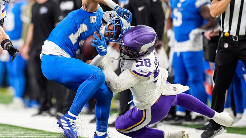 Amon-Ra St. Brown catching a pass while Jonathan Greenard defends during a Lions vs Vikings game