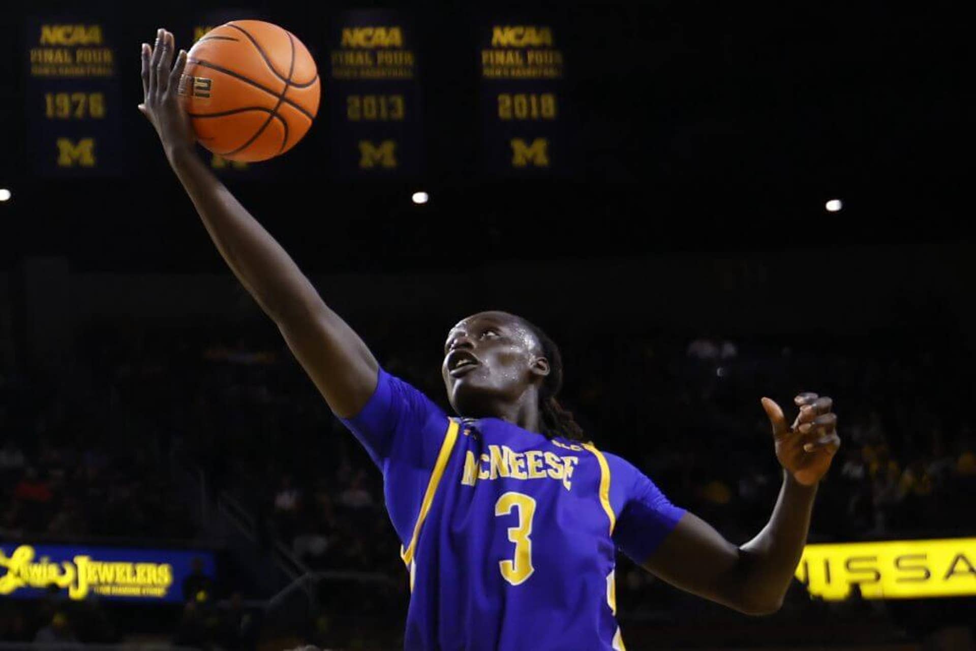 McNeese's Garwey Dual, clad in a blue and yellow McNeese uniform, goes for a finger-roll shot with the ball in his right hand.