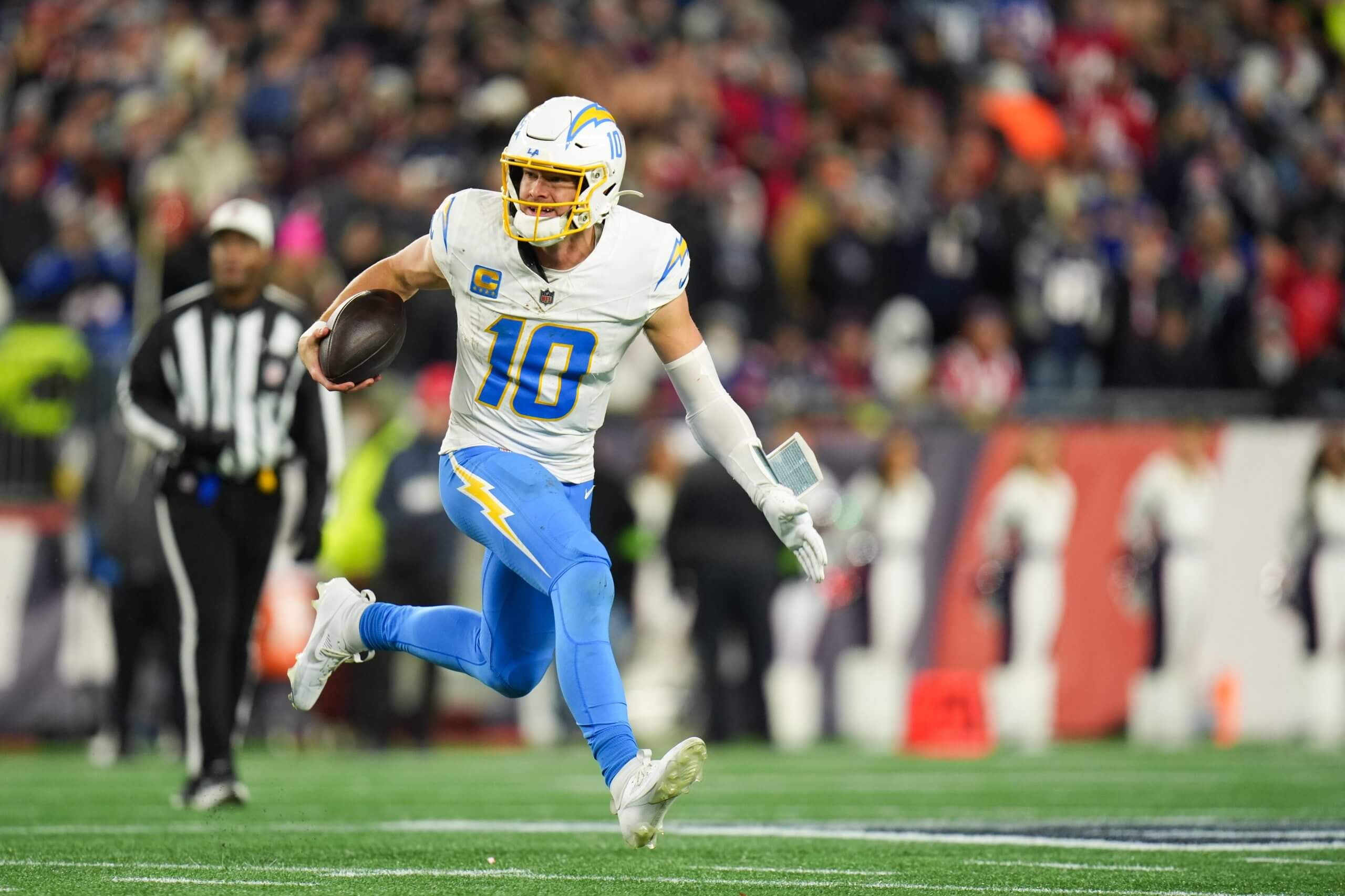 Justin Herbert (10) scrambles during the fourth quarter against the New England Patriots in an AFC Wild Card Round game at Gillette Stadium.