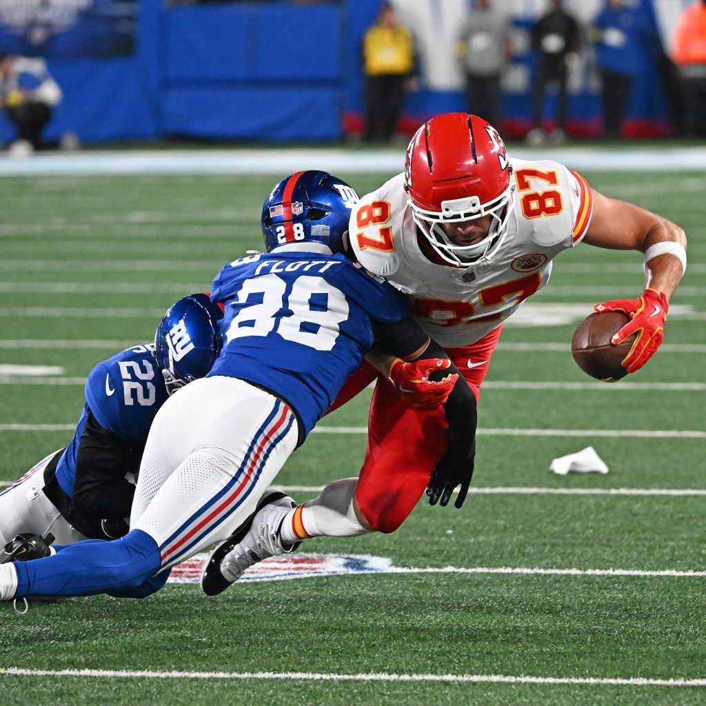 Tight end Travis Kelce running the ball while cornerback Cordale Flott attempts to tackle him.