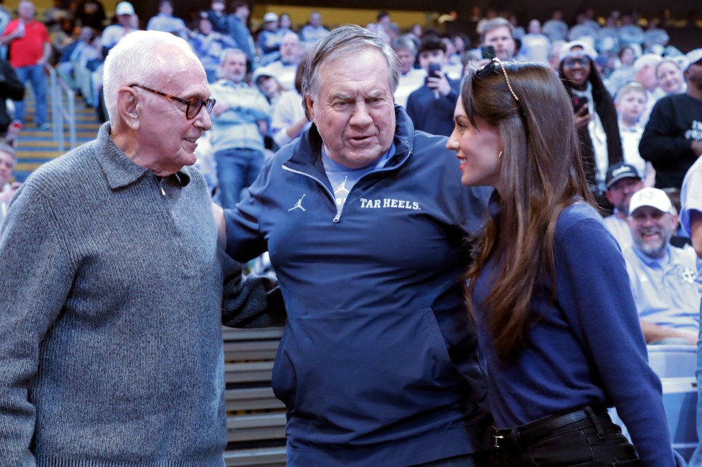 Larry Brown, Bill Belichick, and Jordon Hudson talk during a college basketball game.