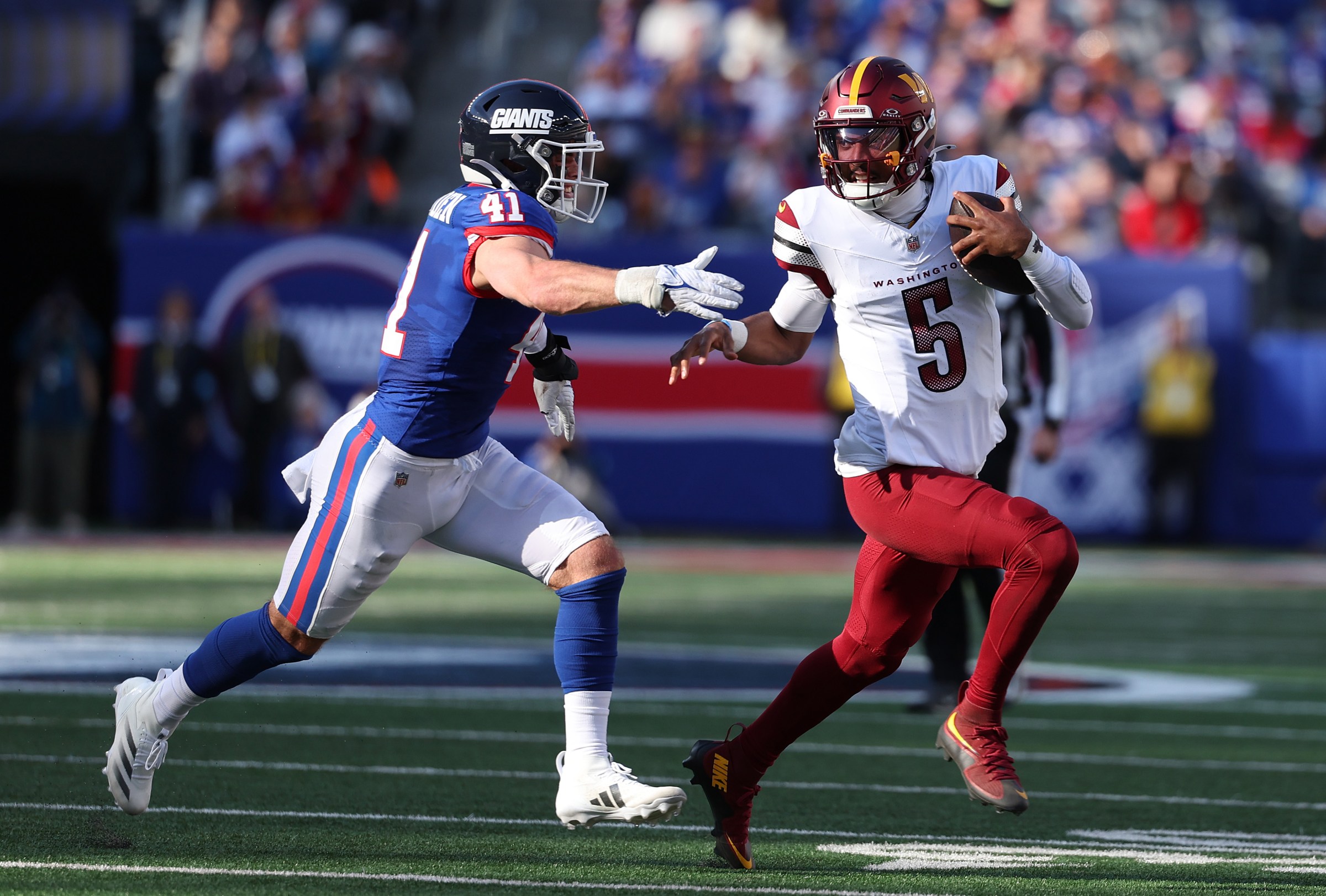EAST RUTHERFORD, NEW JERSEY - NOVEMBER 03: Jayden Daniels #5 of the Washington Commanders is chased by Micah McFadden #41 of the New York Giants during the first half at MetLife Stadium on November 03, 2024 in East Rutherford, New Jersey. (Photo by Al Bello/Getty Images)