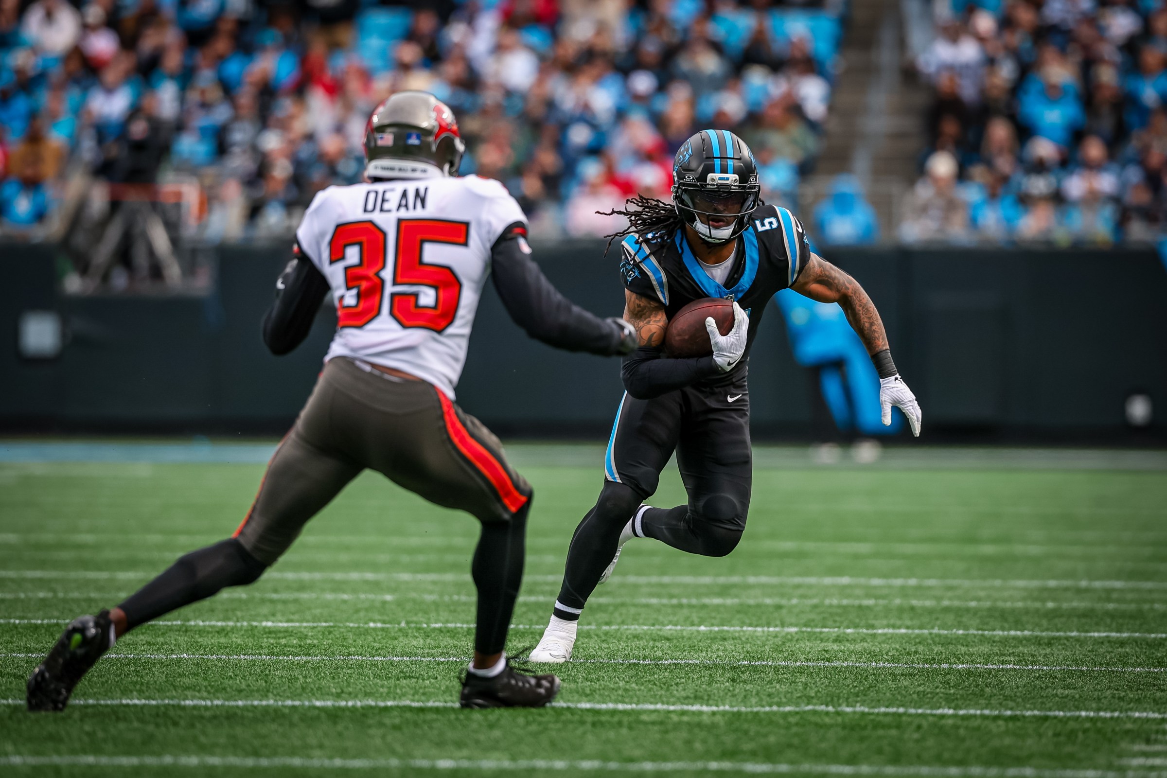 CHARLOTTE, NORTH CAROLINA - DECEMBER 21: Rico Dowdle #5 of the Carolina Panthers avoids a tackle by Jamel Dean #35 of the Tampa Bay Buccaneers during the first half of an NFL game at Bank of America Stadium on December 21, 2025 in Charlotte, North Carolina. (Photo by David Jensen/Getty Images)