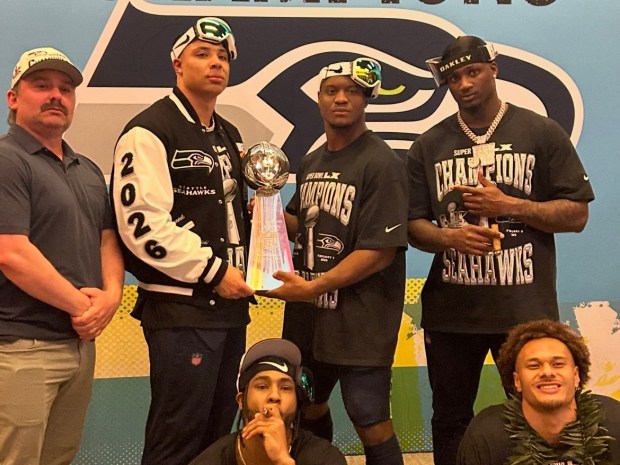 Super Bowl MVP Kenneth Walker (cr.) makes sure fellow Seahawks running back Zach Charbonnet (cl.) grabs his share of the Lombardi Trophy after winning Super Bowl LX in February.