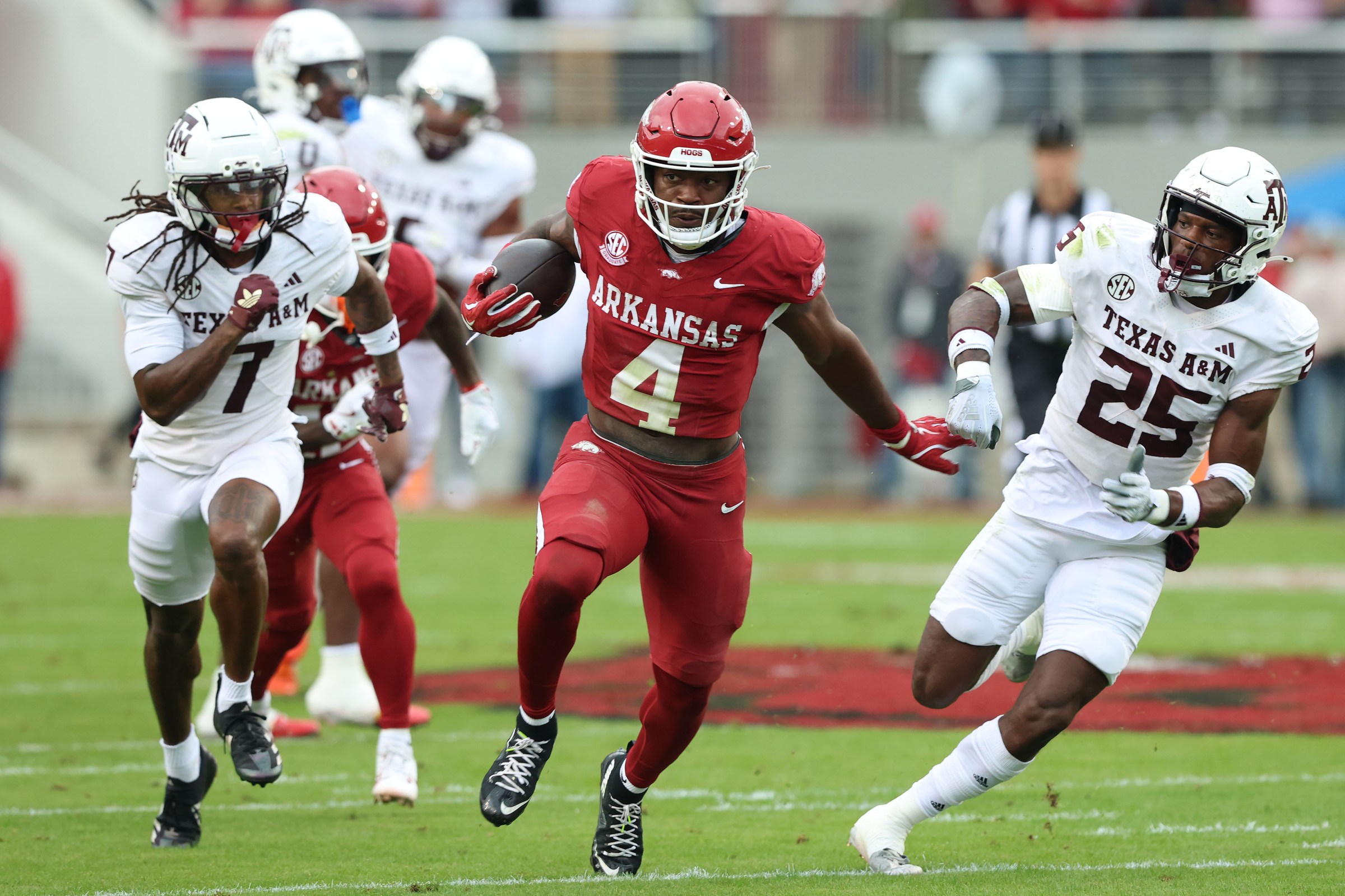 Oct 18, 2025; Fayetteville, Arkansas, USA; Arkansas Razorbacks running back Mike Washington Jr (4) rushes in the second quarter as Texas A&M Aggies cornerback Tyreek Chappell (7) and safety Dalton Brooks (25) defend at Donald W. Reynolds Razorback Stadium. Mandatory Credit: Nelson Chenault-Imagn Images