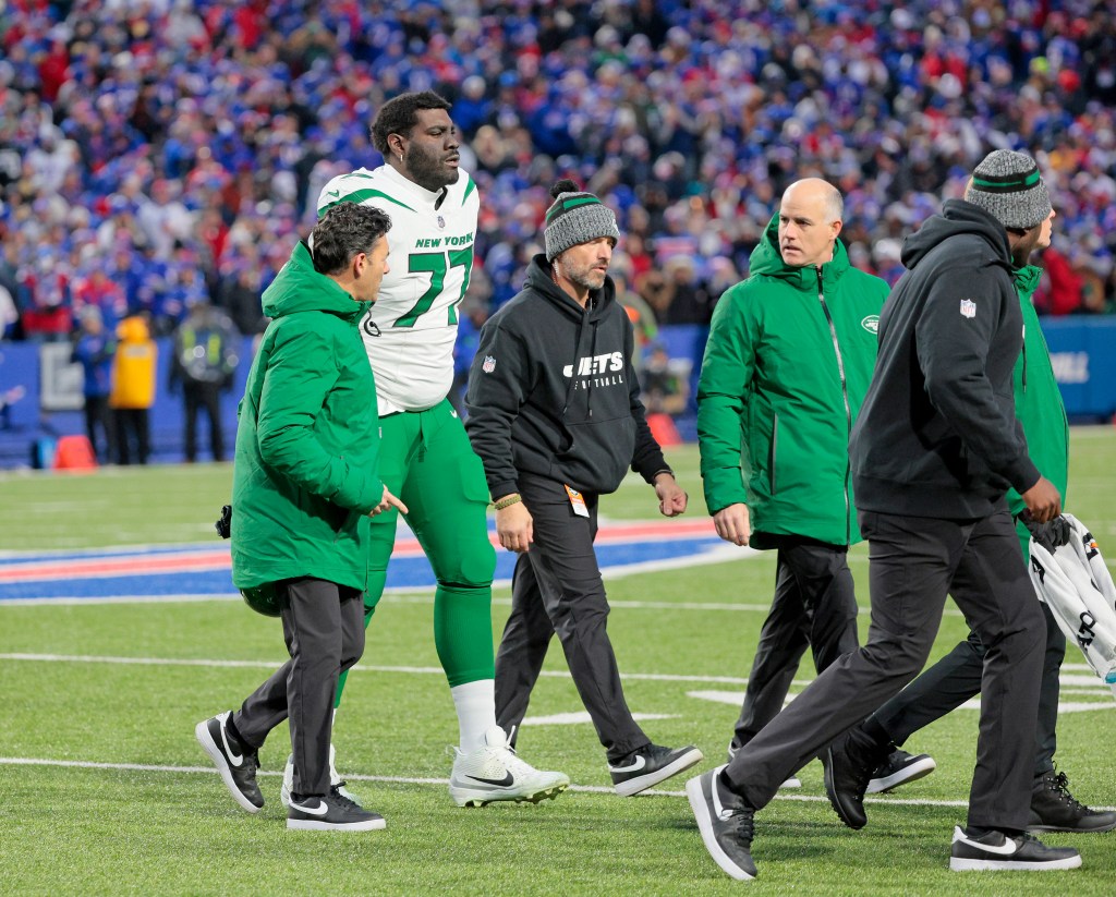 Mekhi Becton (77) walks off with a trainer during a Jets game in November 2023.