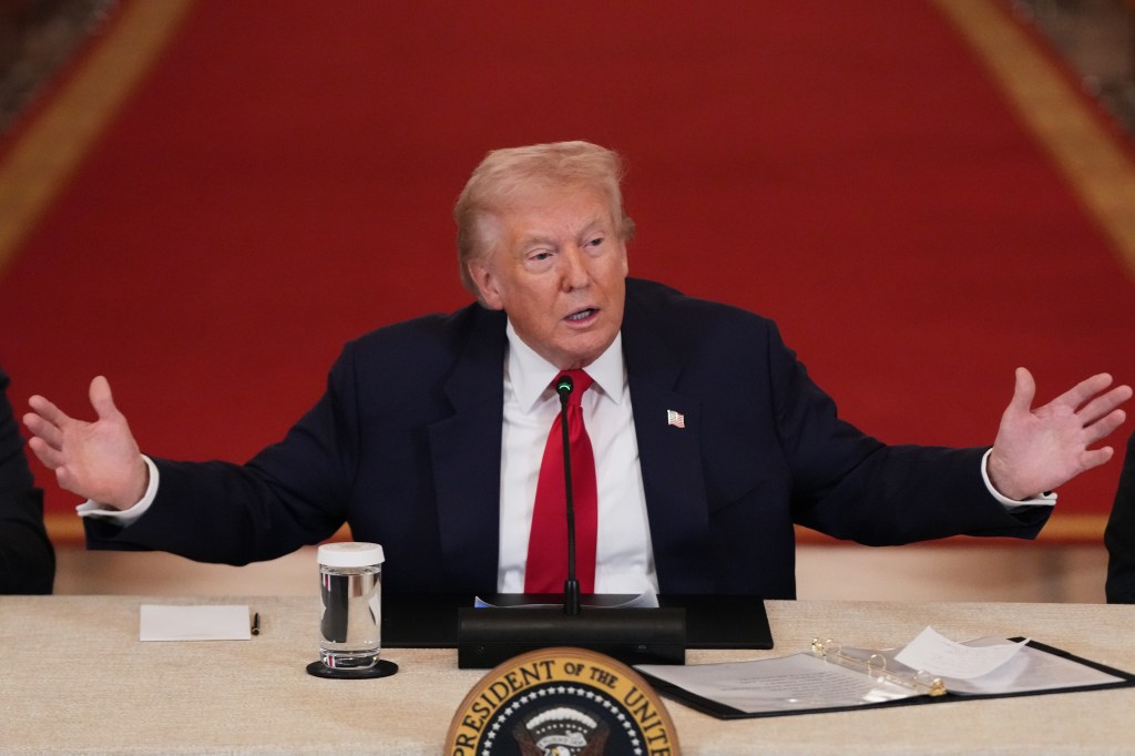President Donald Trump speaking at a roundtable discussion on college sports, with his arms outstretched.