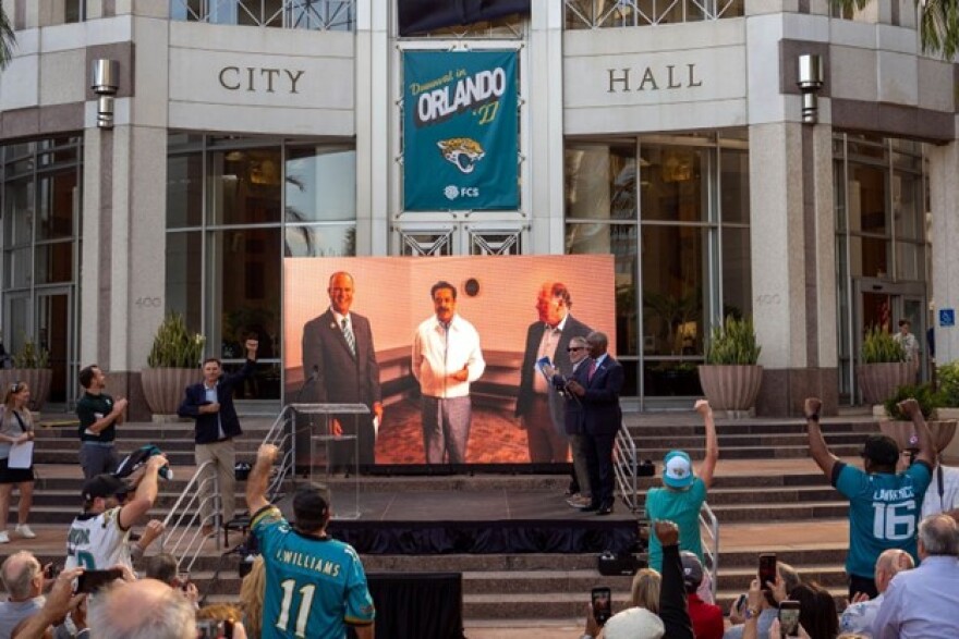 ans cheered in front of Orlando City Hall on Tuesday evening as Jacksonville Jaguars owner Shahid Khan, center, announced that Orlando's Camping World Stadium would host his team during the 2027 NFL season.
