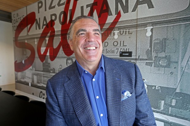 Sal Lupoli next to a blown-up photo of his grandparents first pizza shop in Revere. (Stuart Cahill/Boston Herald)